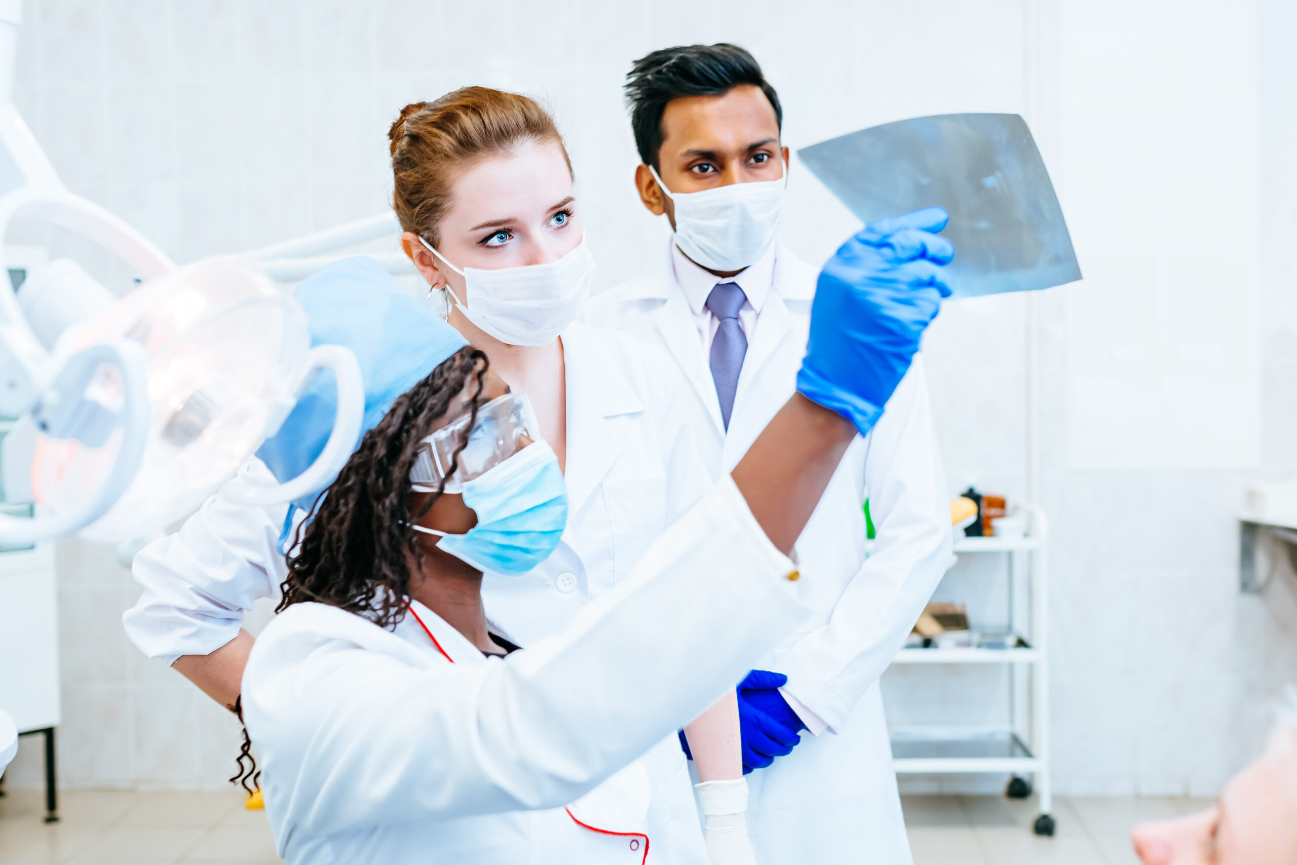 Multiracial dental team checking teeth x ray of patient. Dental clinic
