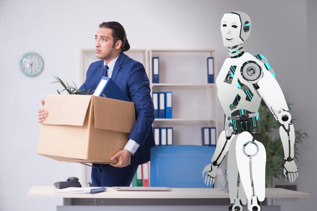 The picture shows a sad office worker carrying a box of his belongings. He is being replaced by a robot.