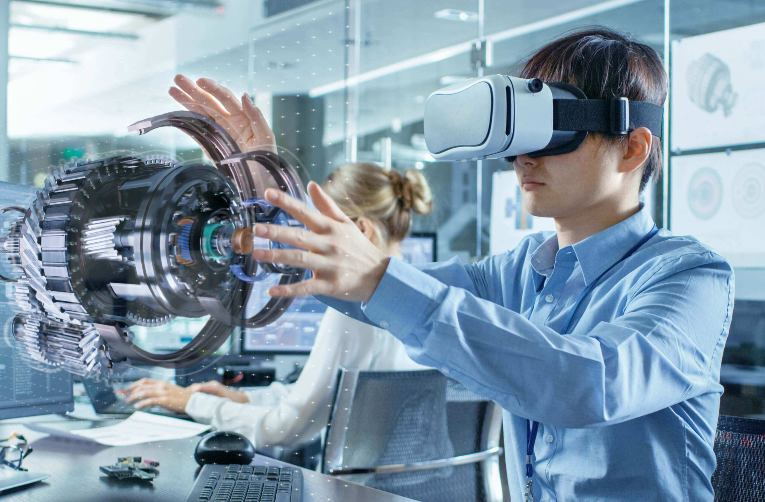 A student wearing a virtual reality headset is working on a 3D model of a mechanical part