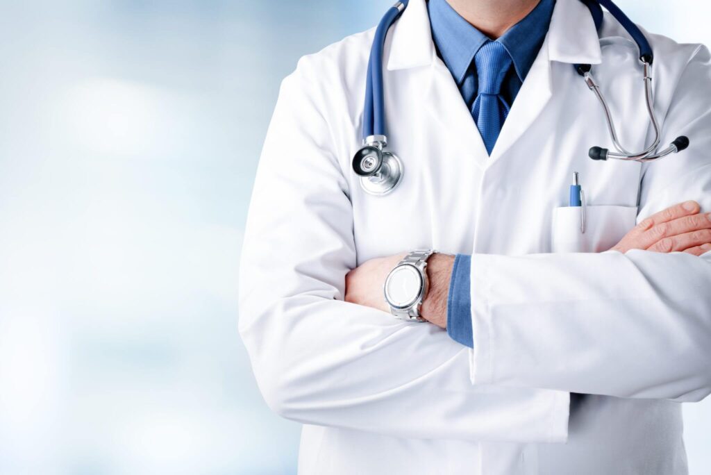 A male doctor wearing a white coat, standing confidently with a stethoscope around his neck in a clinical setting - Webco Marketing Medical Blogs